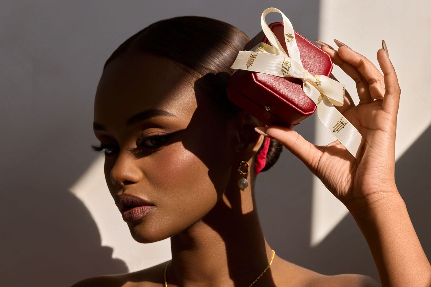 A person holds a red heart-shaped box near their face, casting dramatic shadows in warm lighting.