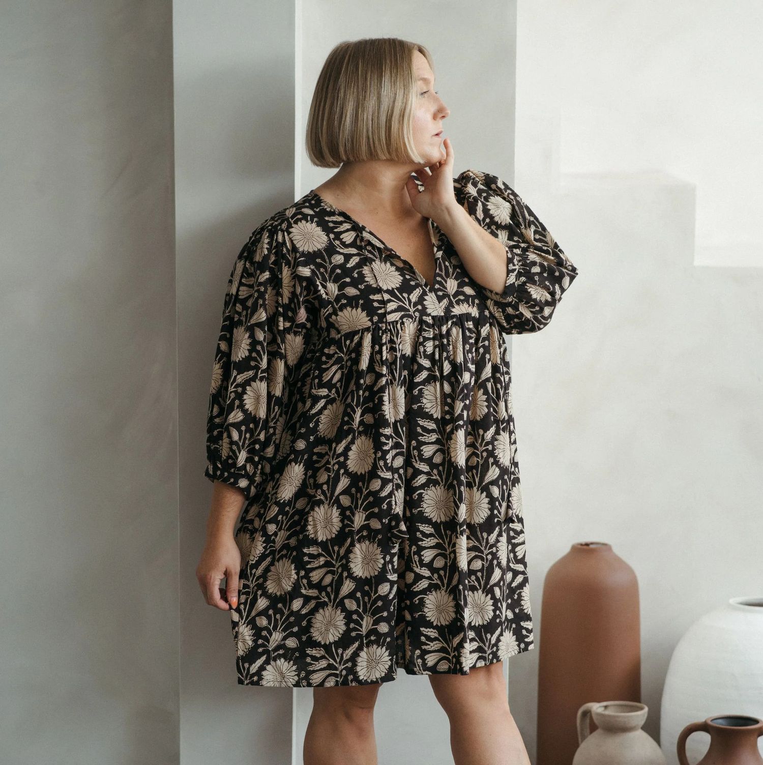 A sequence of photos showing a person in a floral printed dress posing against a white wall near a window.