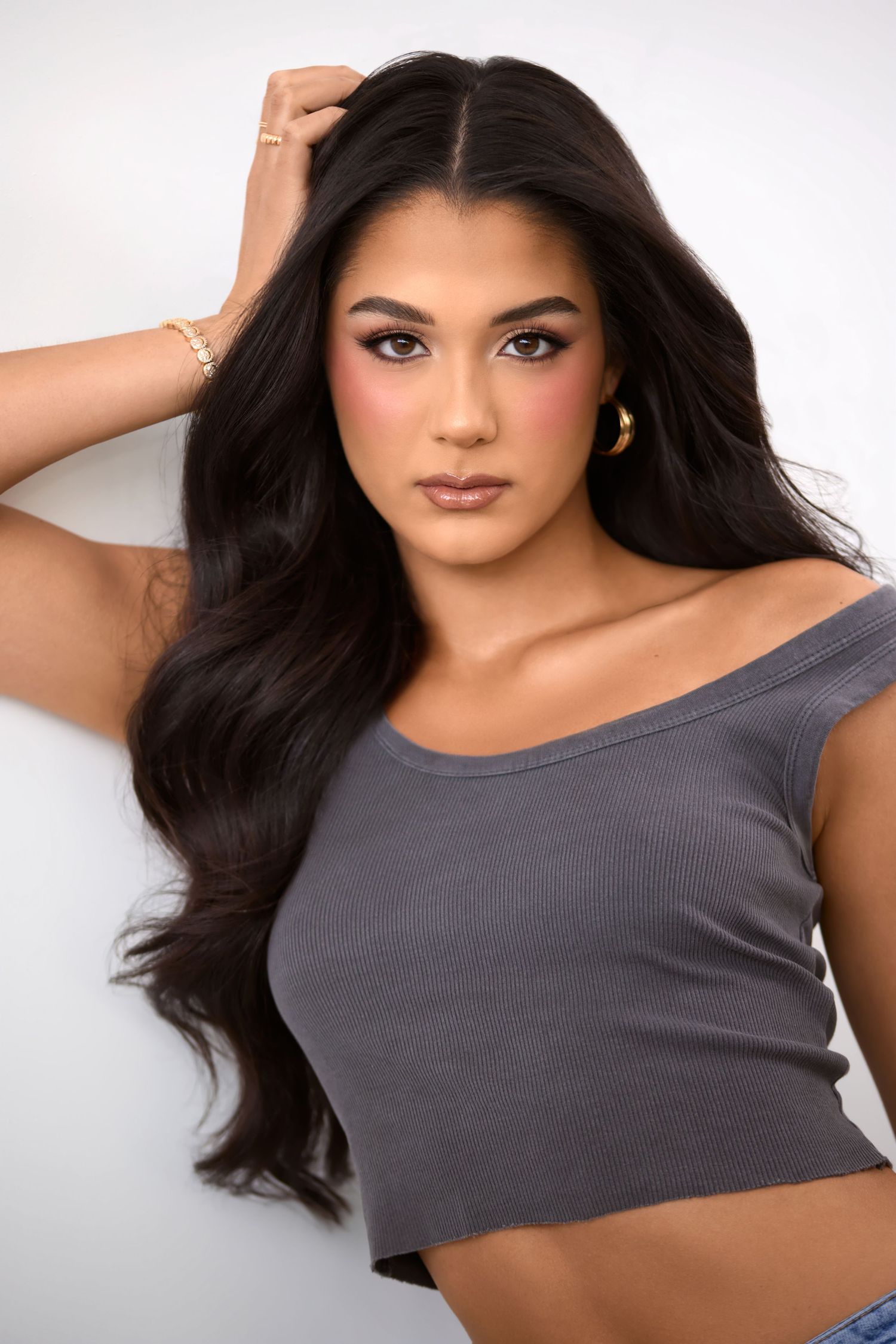 Portrait featuring long dark hair and natural makeup against white background.