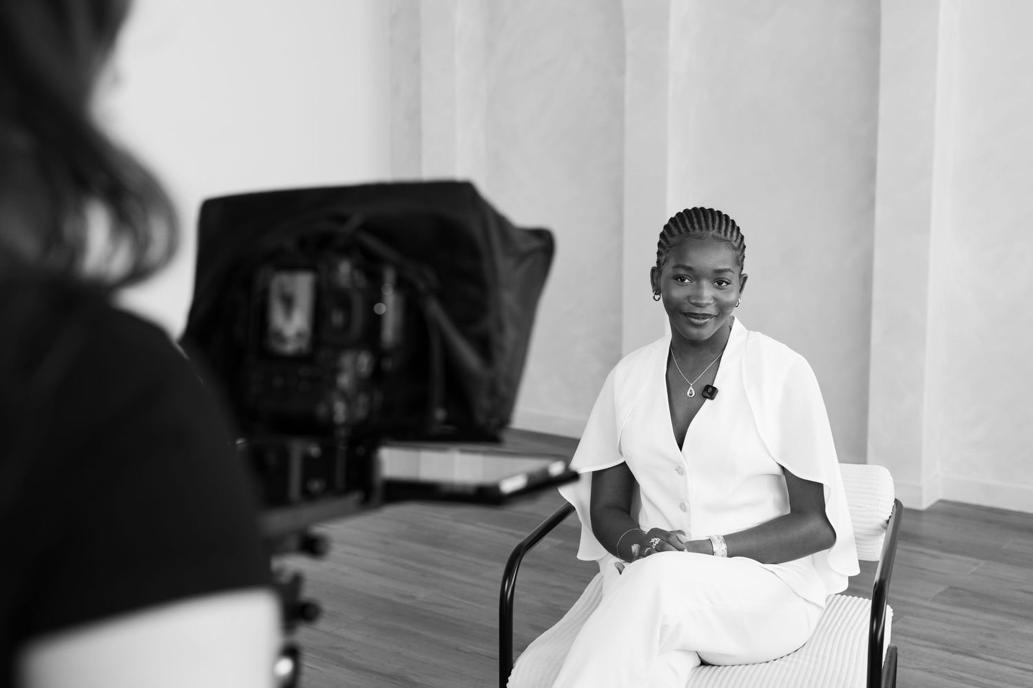 Black and white photo of a healthcare worker in white uniform sitting in a chair during an interview.