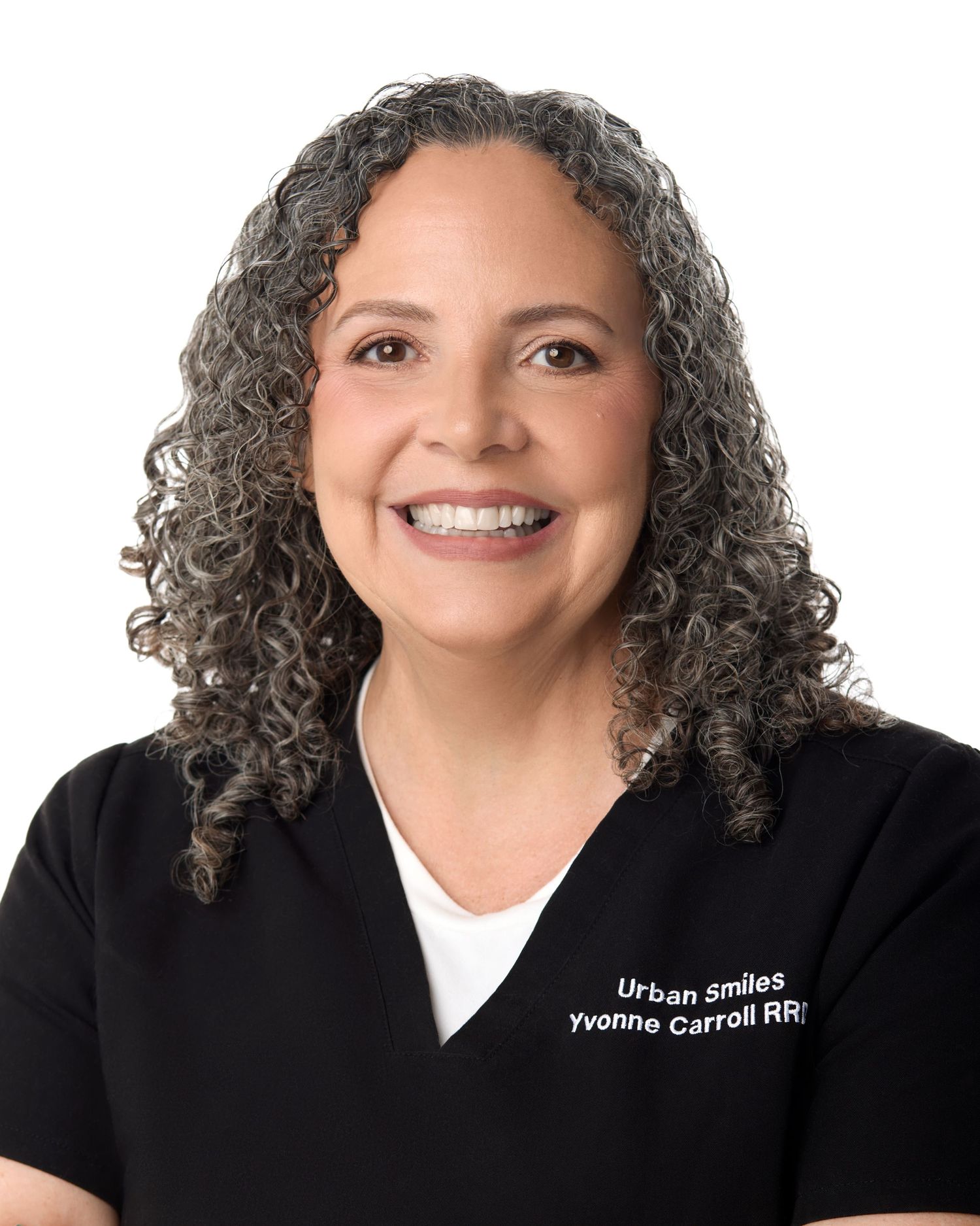 Yvonne Carroll RDH smiling in black Urban Smiles scrubs, professional dental hygienist headshot.