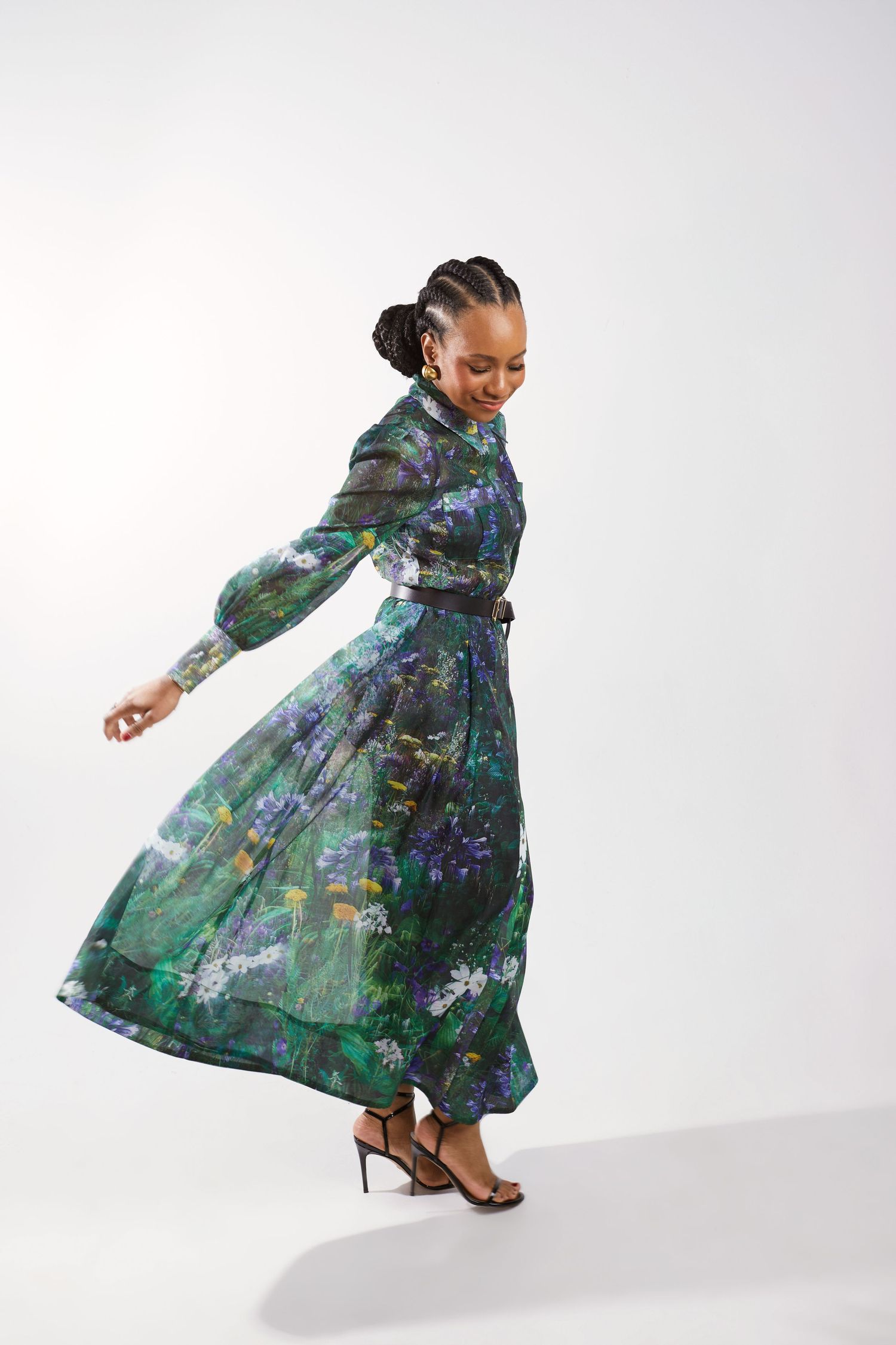 A flowing green and blue watercolor printed dress twirls gracefully in motion against a white background.