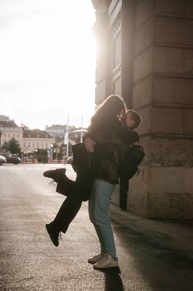 Paarfotografie in Wien: Mann habt seine Frau hoch und küsst sie am Wiener Heldentor in der untergehenden Sonne