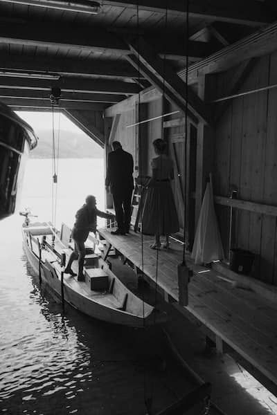 Schwarz-weiß Foto von einem Bootshaus am Grundlsee - Die Braut steigt in das kleine Boot.