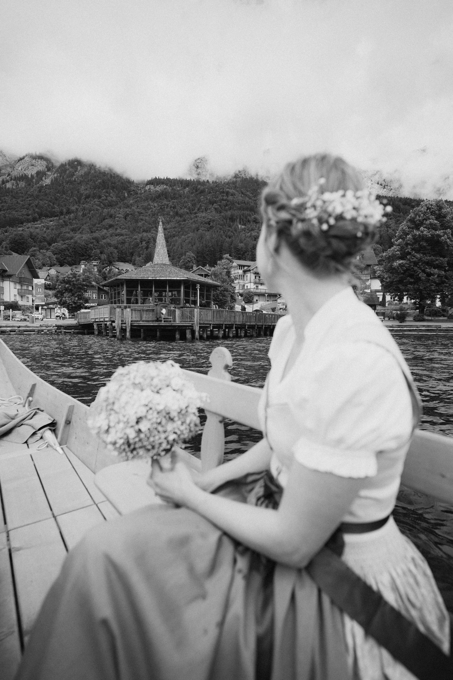 Braut in Trächt fährt auf einem Boot über den Grundlsee und blickt Richtung Pavillon indem die Trauung stattfindet