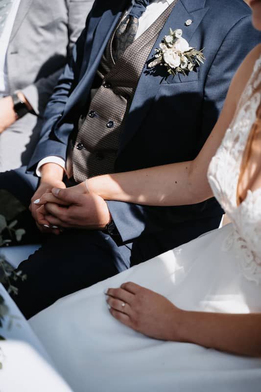 Hochzeitsfotografie in Niederösterreich: Braut und Bräutigam halten während der Zeremonie Händchen
