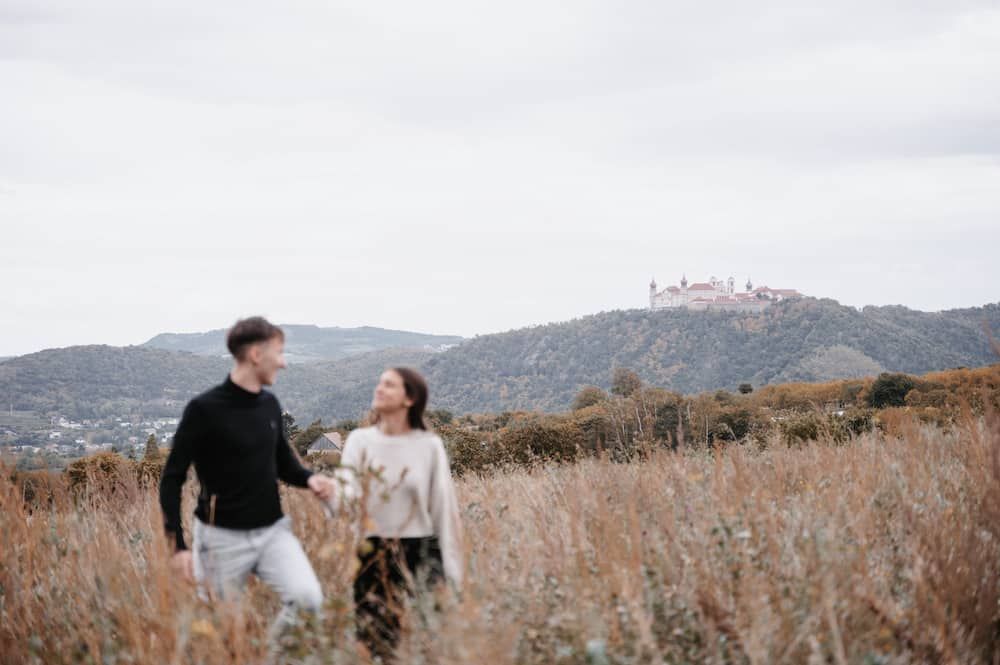 Paarfotos in der Wachau, das Paar geht über eine Wiese spazieren.