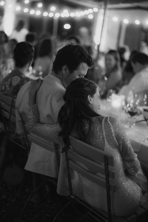 Black and white photo of a couple sharing an intimate moment at an elegant outdoor wedding reception dinner.