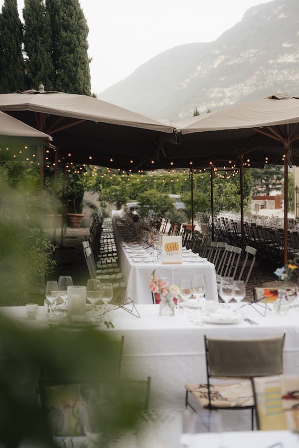 Elegant outdoor wedding reception with long white tables, string lights, and mountain views.