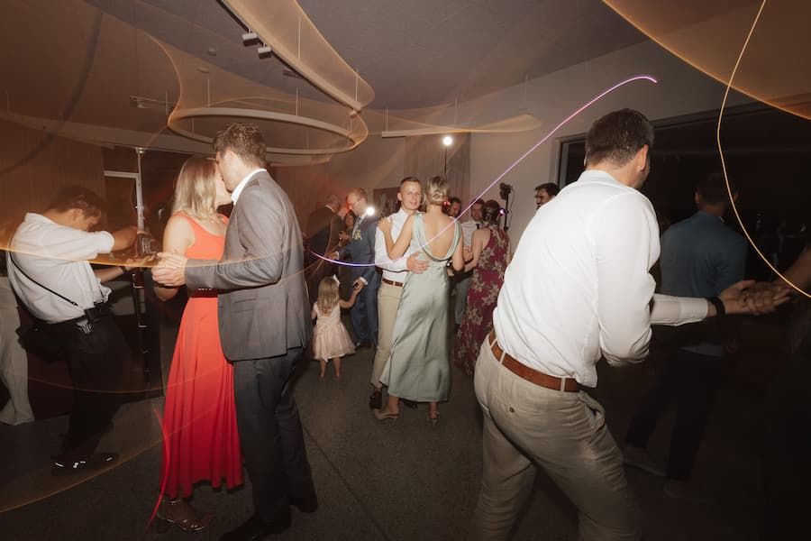 Guests dancing and celebrating at an elegant wedding reception with warm ambient lighting.