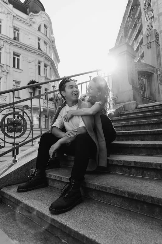 Laura & Dhan sitzen auf Stufen in Wien und lachen sich an