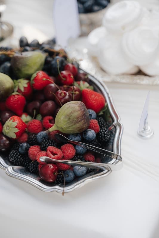 Silver platter filled with fresh mixed berries including raspberries, blueberries, blackberries, cherries, strawberries, and figs.
