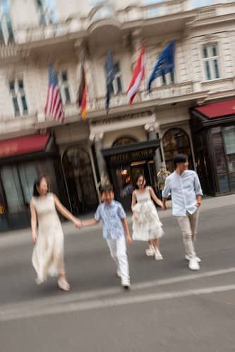 Familie spaziert zu viert vor dem Hotel Sacher über die Straße. Das ganze ist mit Motion Blur aufgenommen