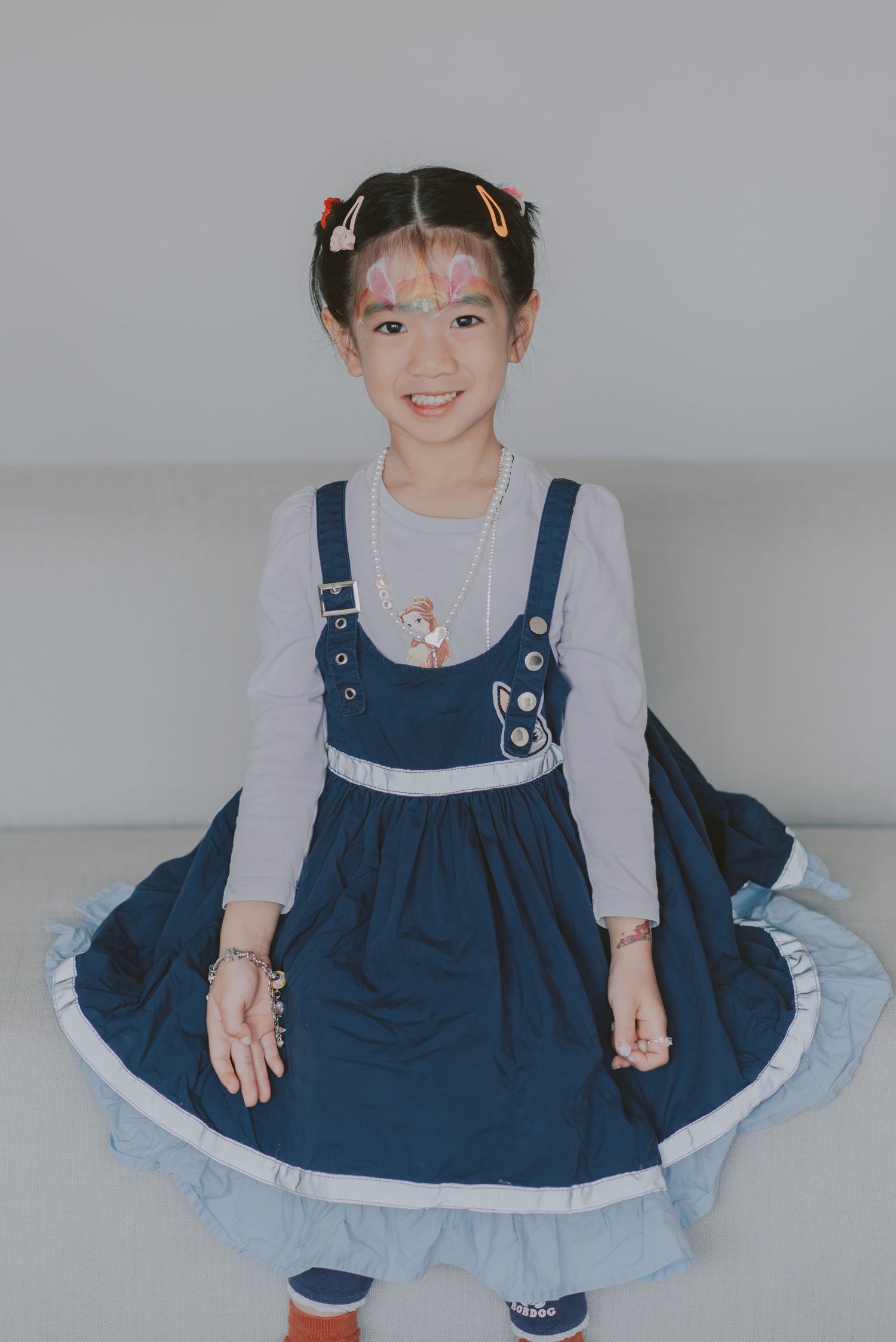 A girl posing in front of the camera for her portrait in a studio setting.