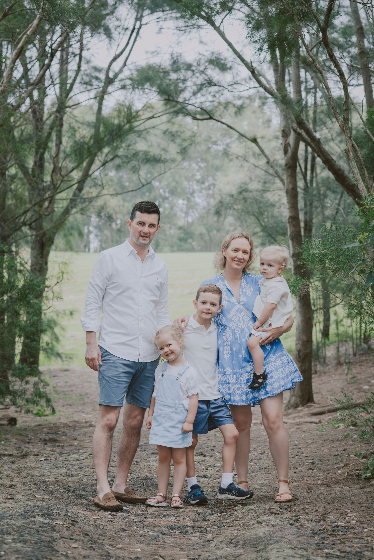 A family of five, posting in front of a camera for their family portraits.