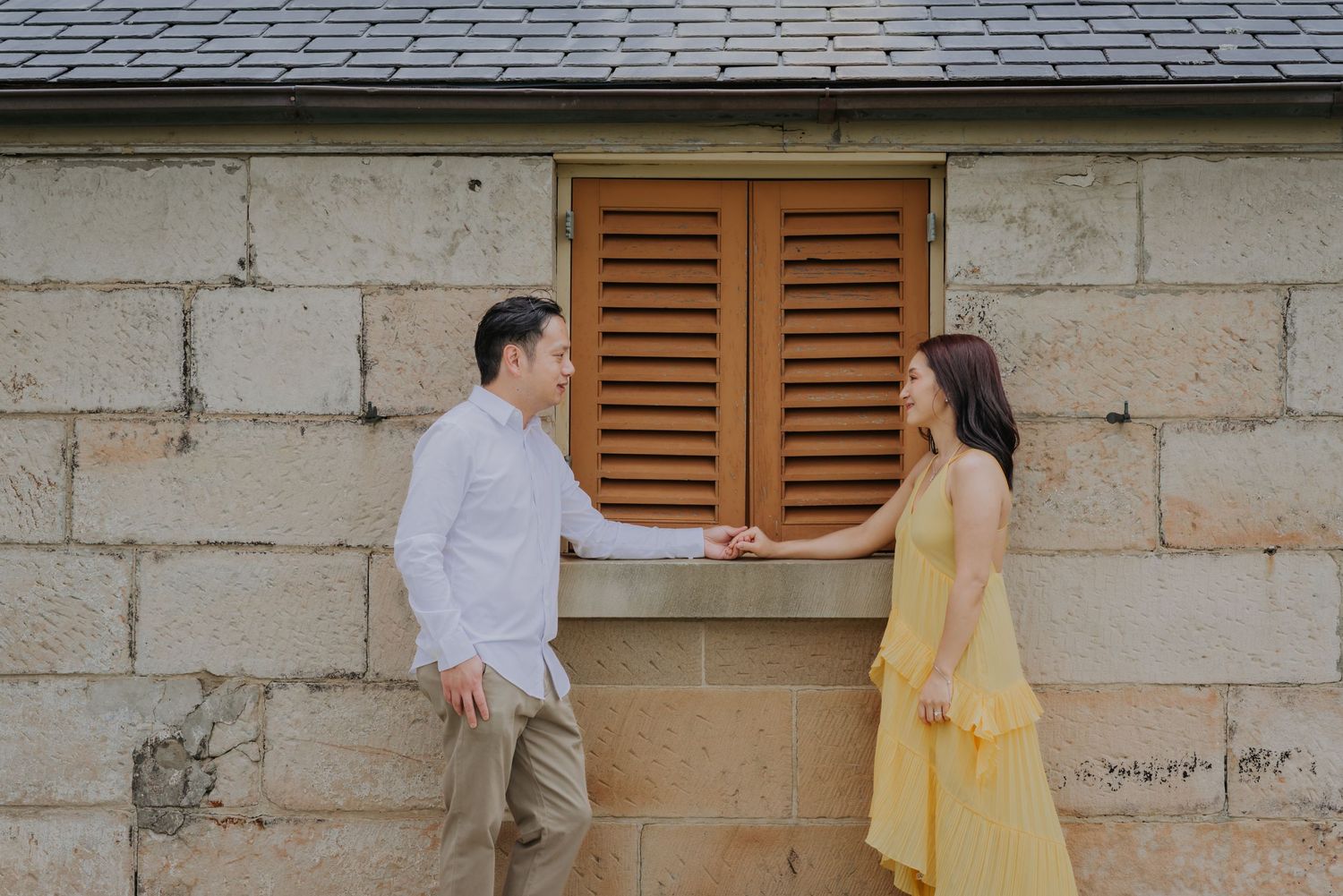 A couple holding hands and posting in front of a camera for their portraits.