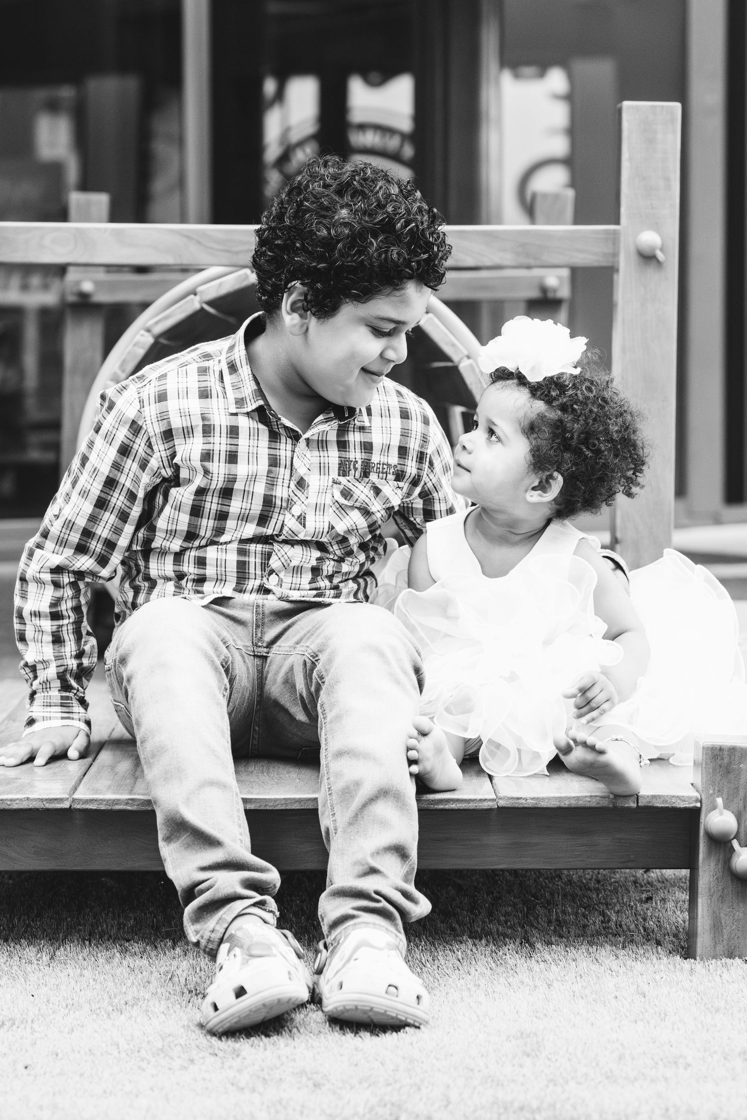 Brother and sister looking at each other while posing for their portrait, showing a lovely connection and sibling love.