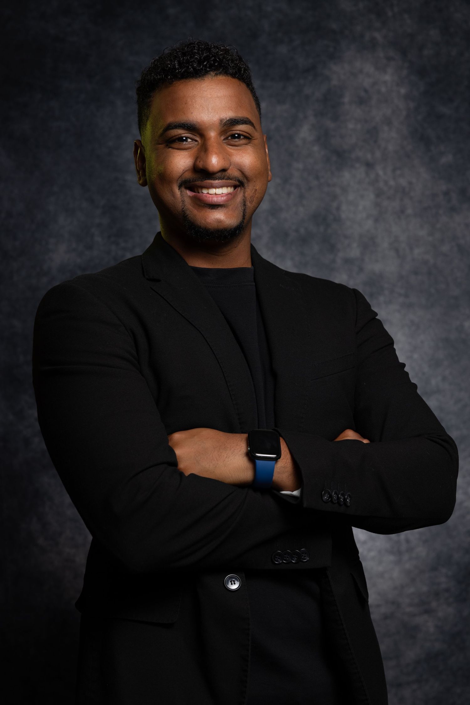 Professional headshot portrait series of person in black attire against dark gray background wearing smart watch.