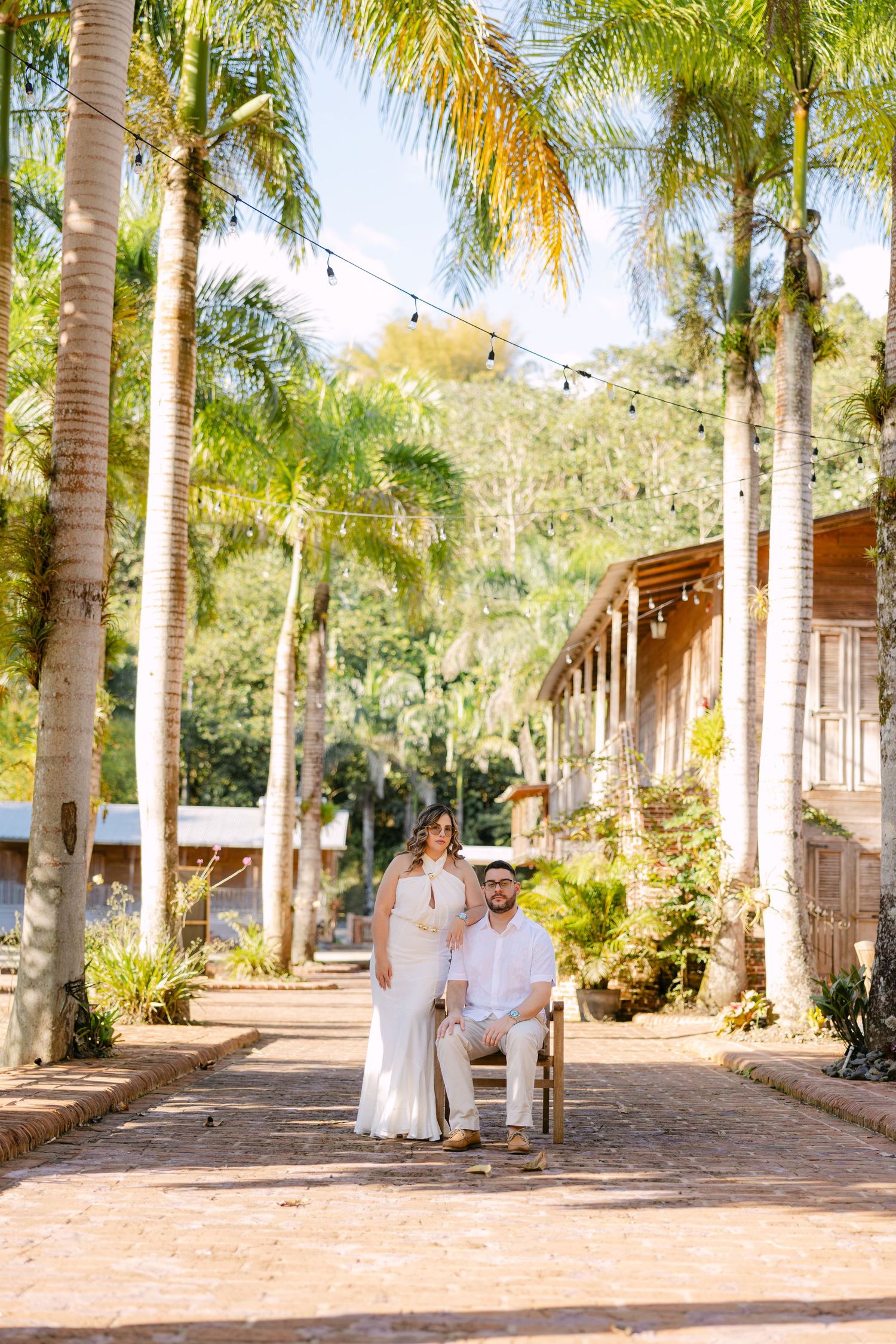Palm trees line a rustic path at a tropical venue with string lights overhead creating a romantic atmosphere.