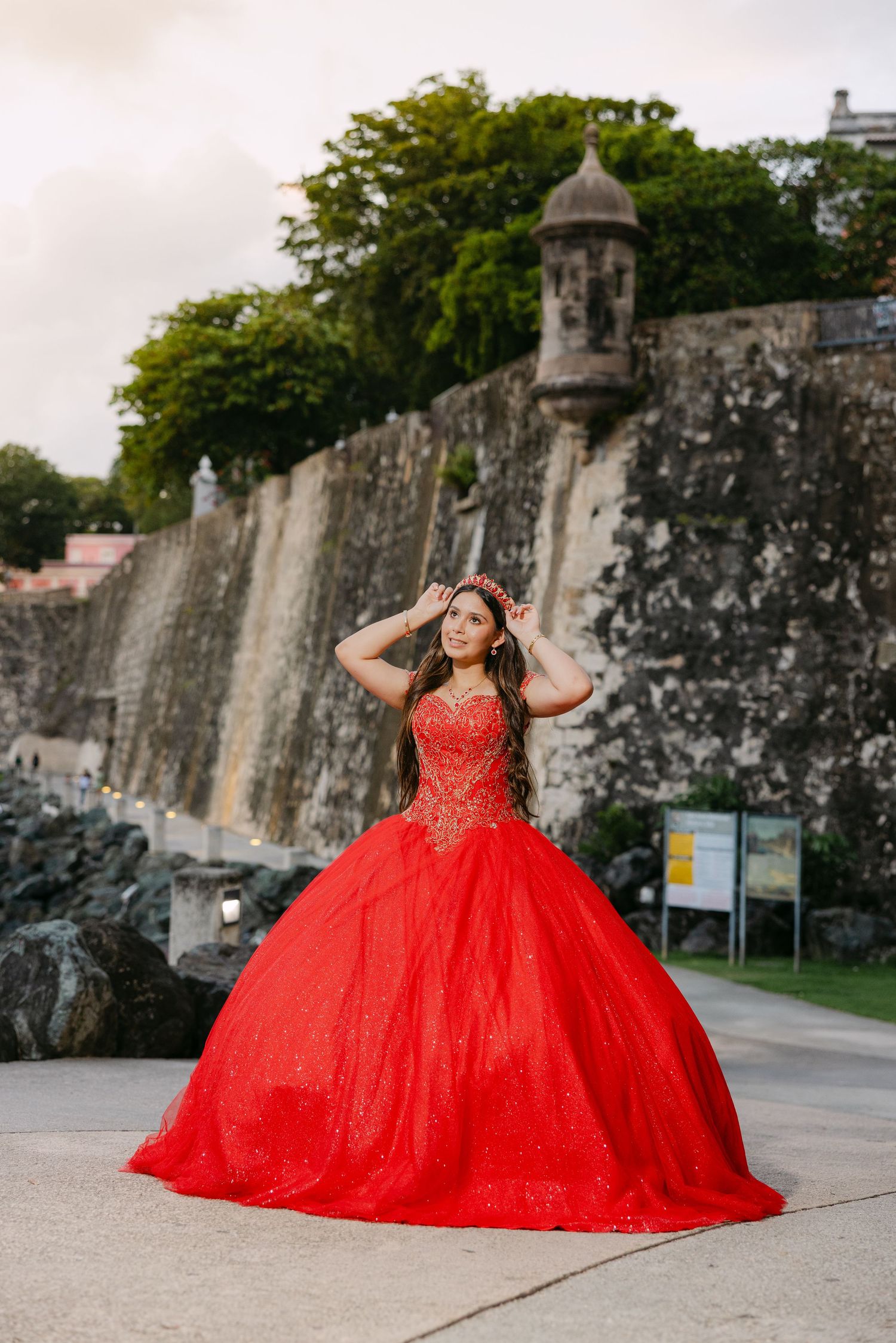 A stunning red ballgown dress photoshoot against historic stone fortress walls in Old San Juan.