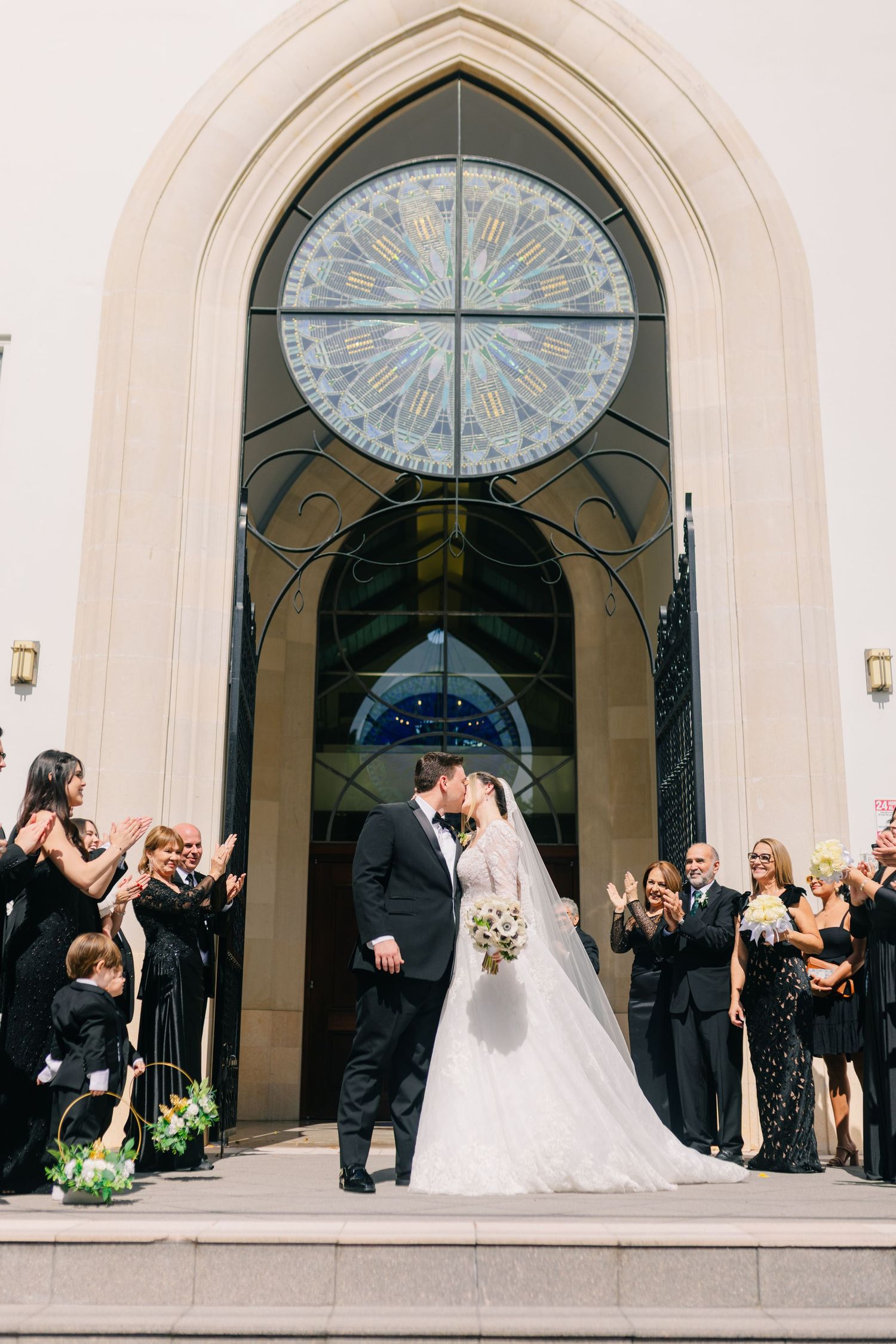 A wedding ceremony exit under a beautiful stained glass window with guests celebrating.
