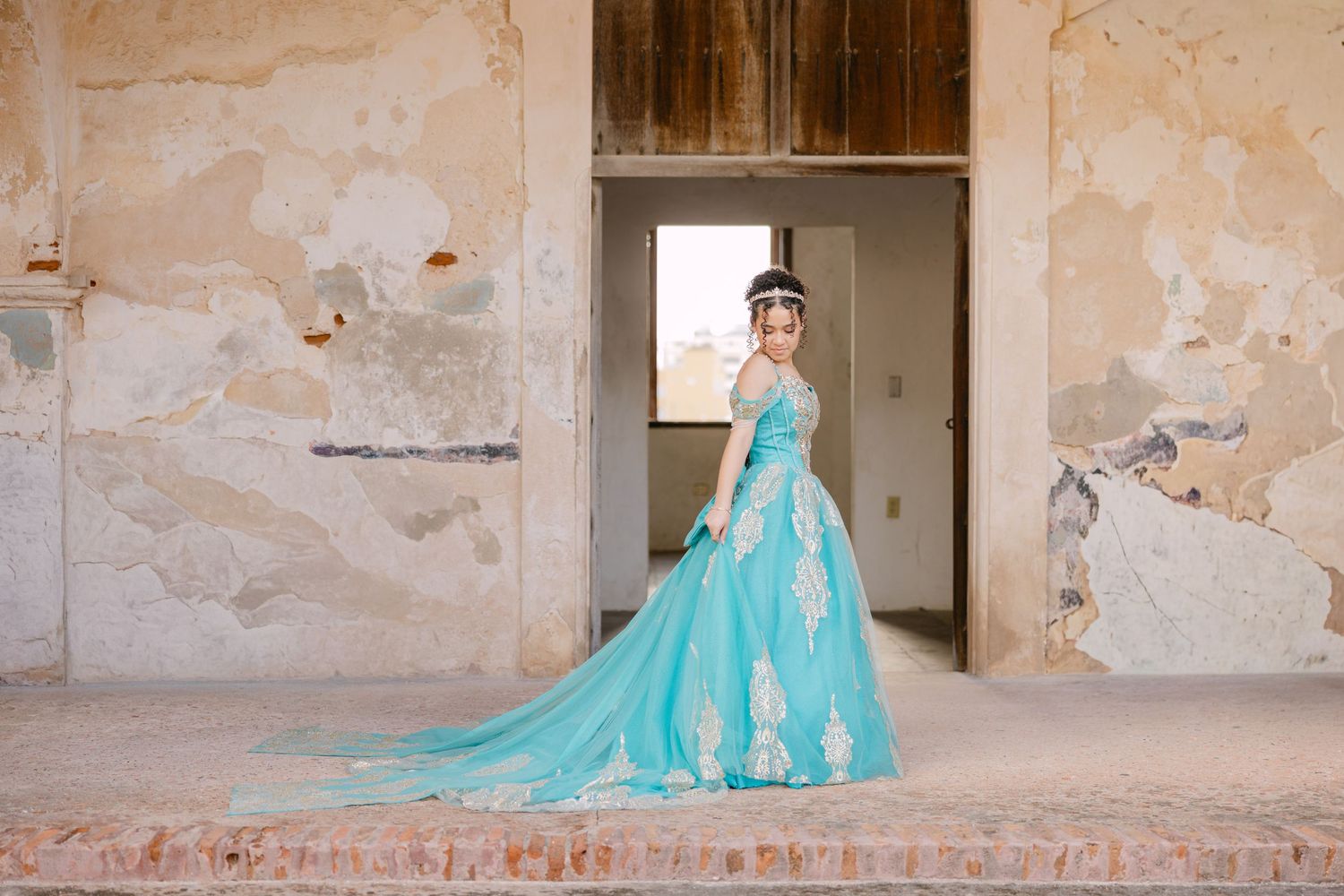 A person in a flowing turquoise gown poses in an elegant sequence against weathered stone walls.