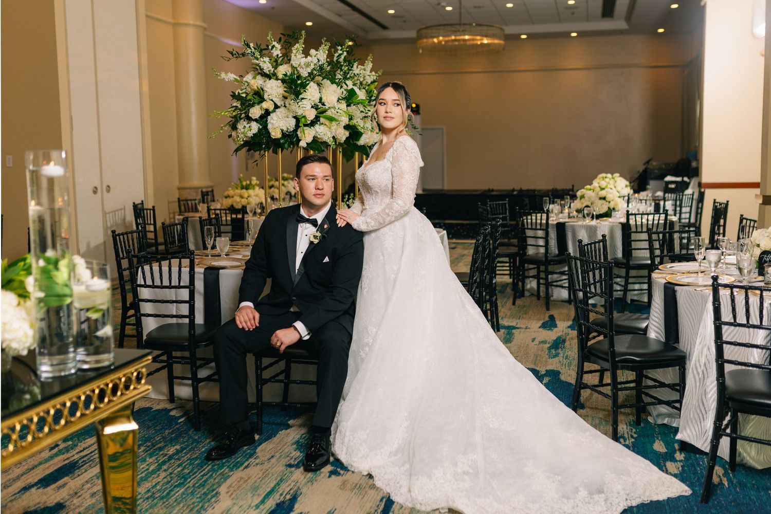 Wedding couple posing in elegant reception venue with floral decorations.