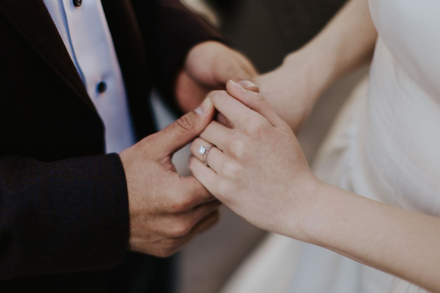 Close-up of hands exchanging rings during a wedding ceremony.