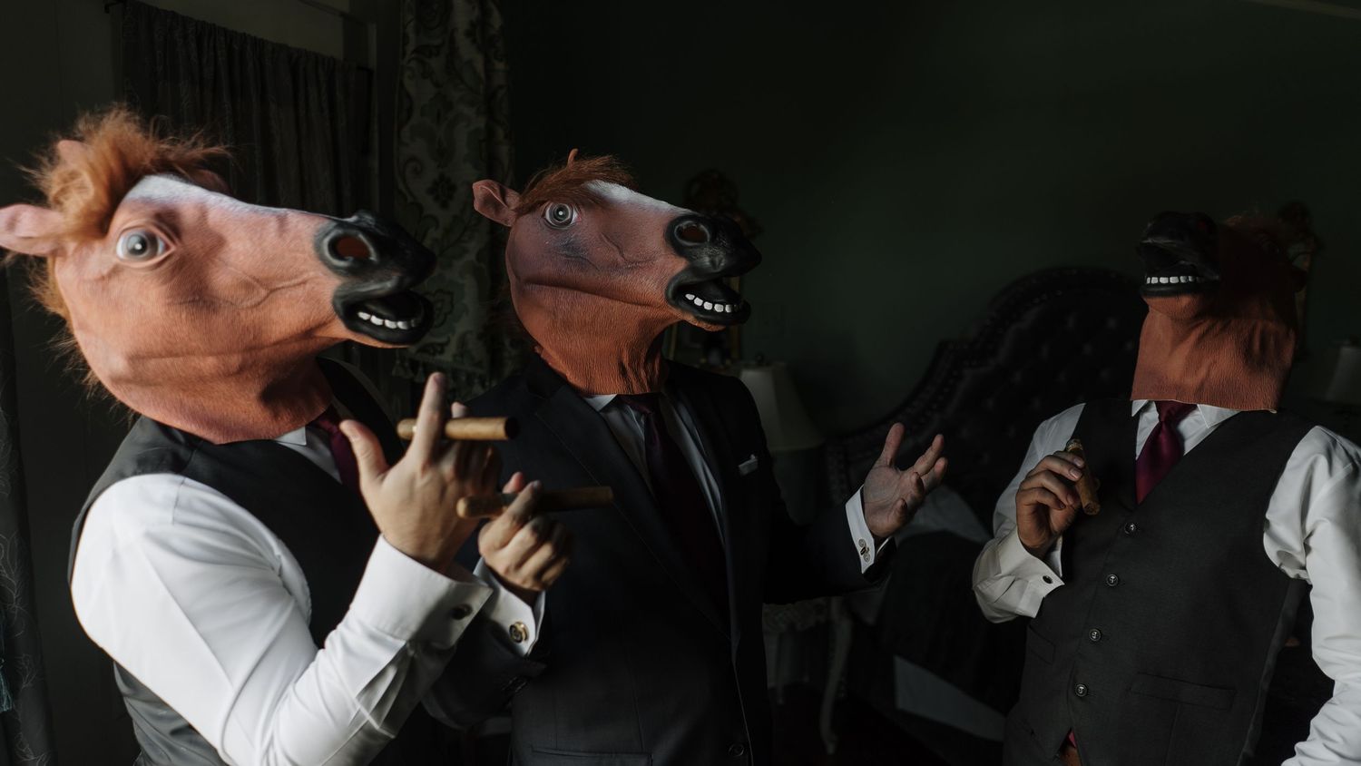 Three people in suits wearing realistic horse head masks pose together in a dimly lit room.
