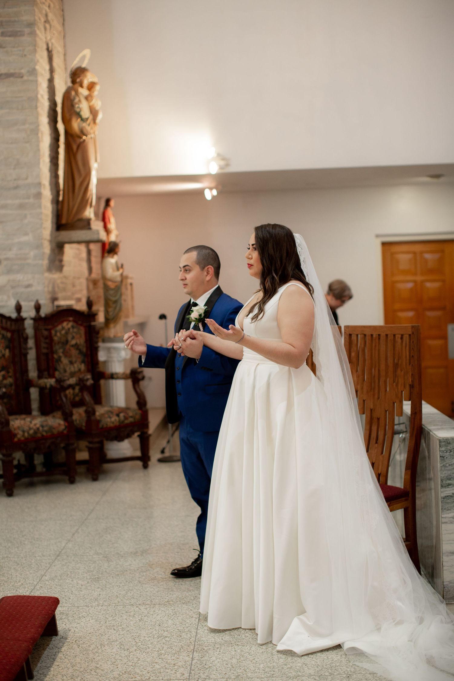 Bride and groom holding hands at the altar during a Catholic church wedding ceremony.