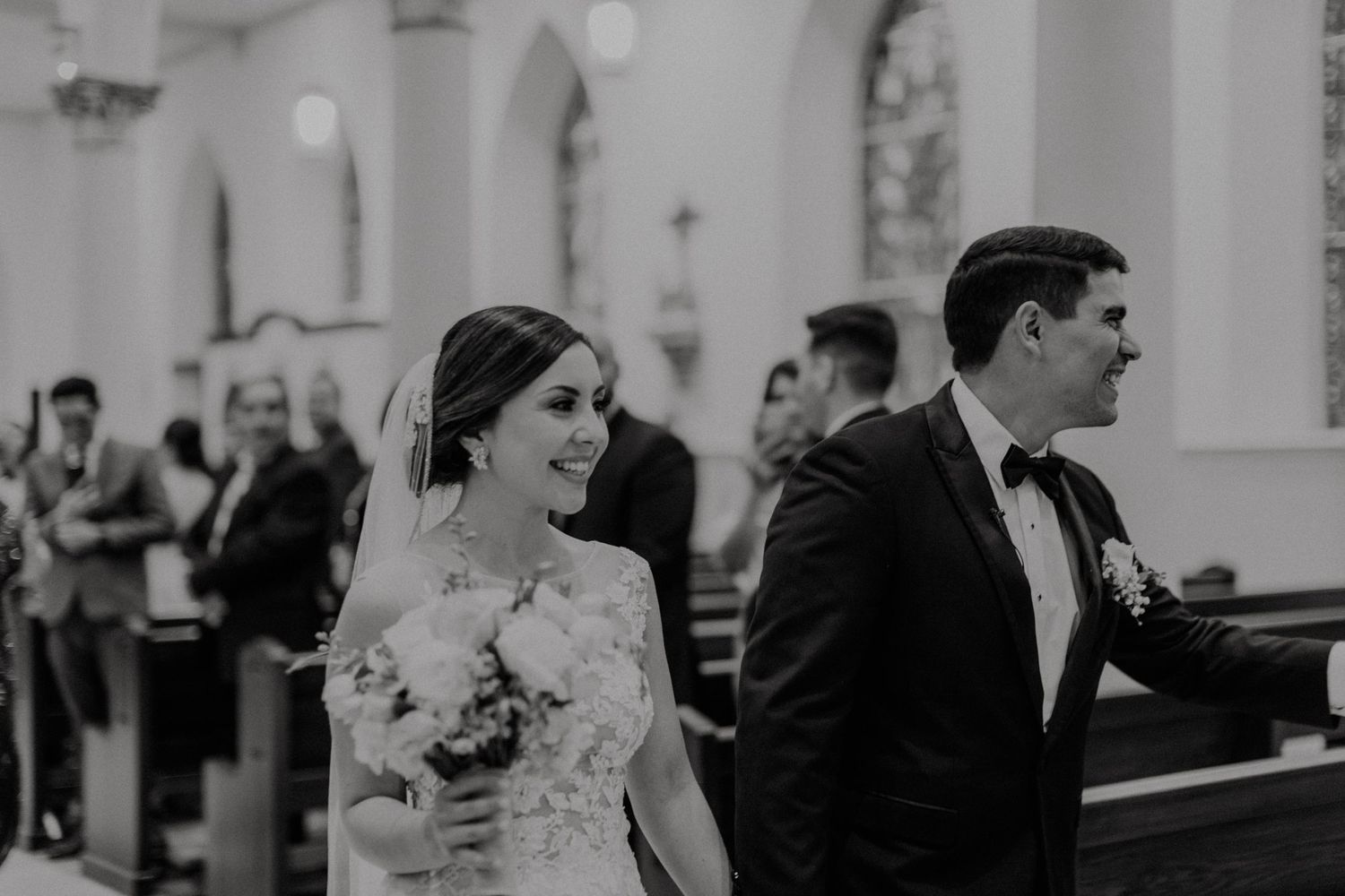 Black and white photo of a wedding ceremony in a traditional church with ornate architecture.