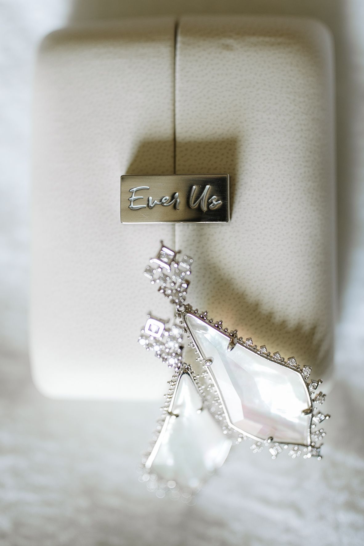Elegant diamond drop earrings displayed beside Ever Us branded ivory jewelry box.