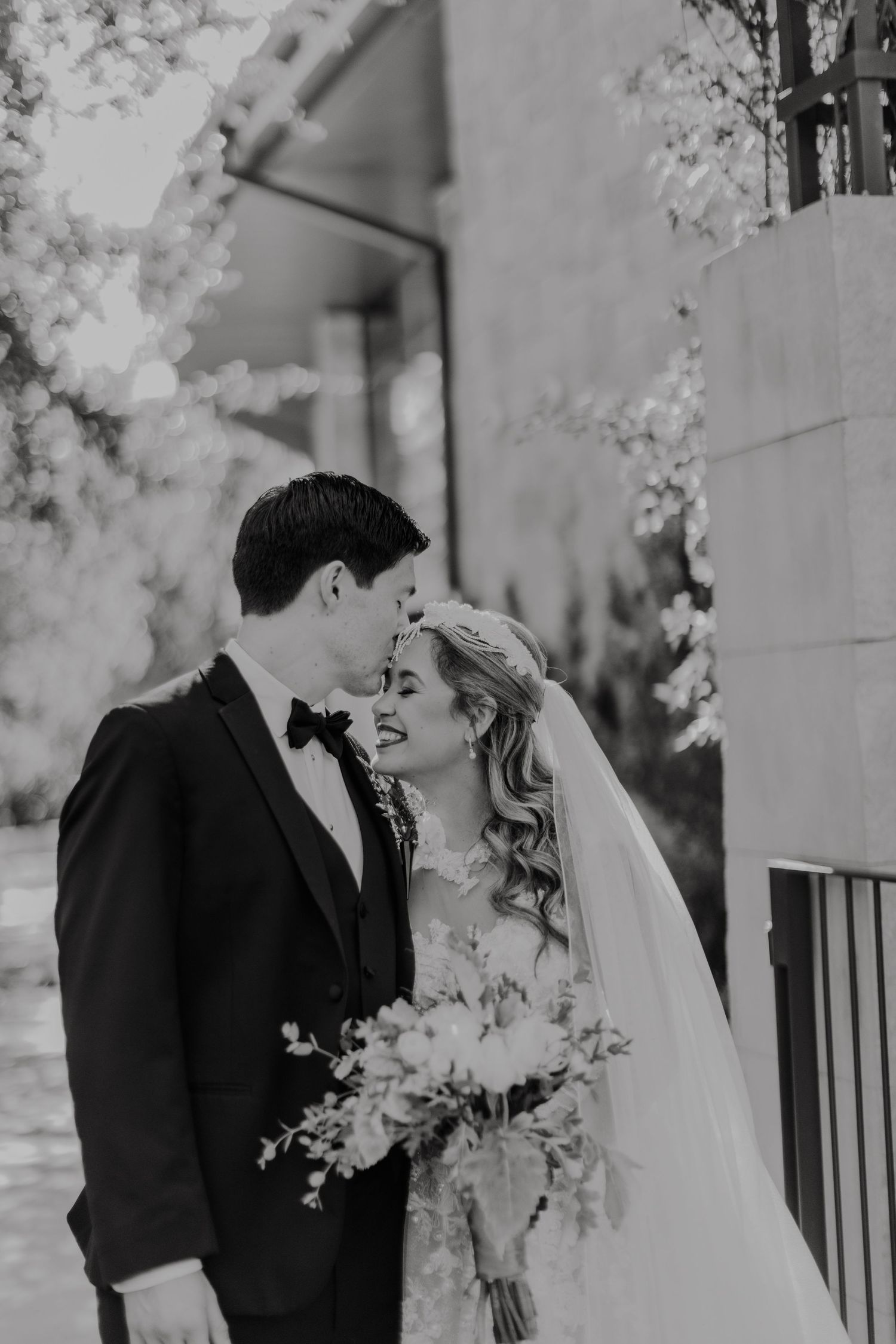 Romantic black and white wedding portrait captured among blooming trees.