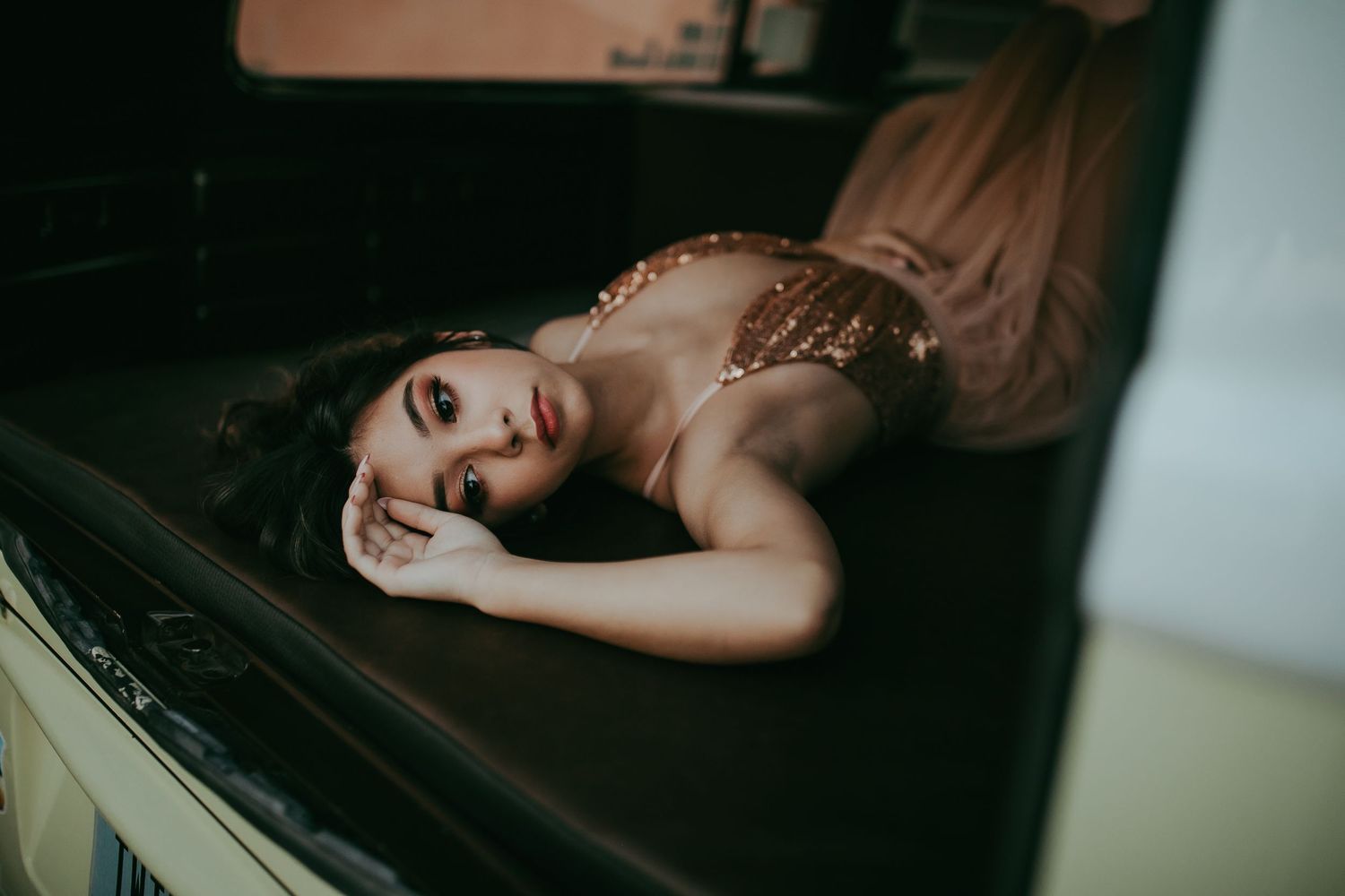 Dramatic moody boudoir portrait of someone lying on dark piano surface in lace dress.