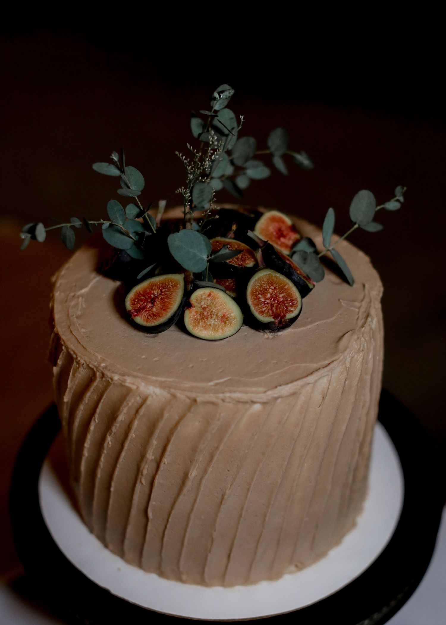 Single-tier caramel buttercream wedding cake topped with fresh figs and eucalyptus greenery.