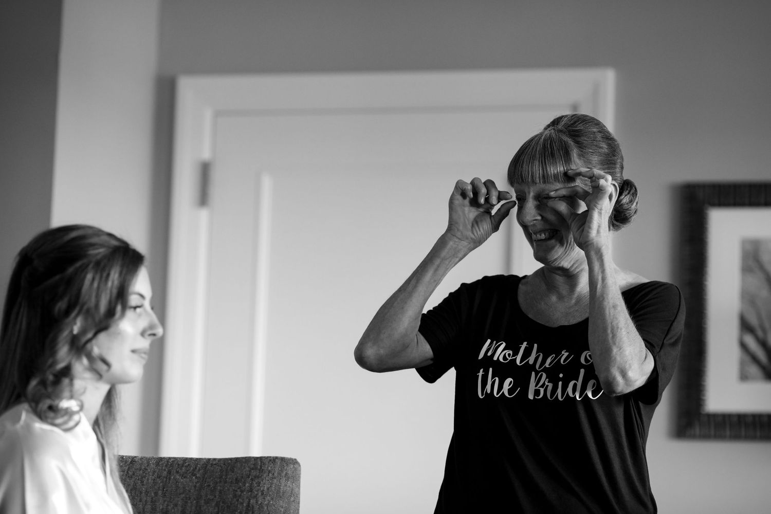 Emotional mother of the bride wiping tears in black and white wedding preparation photo.