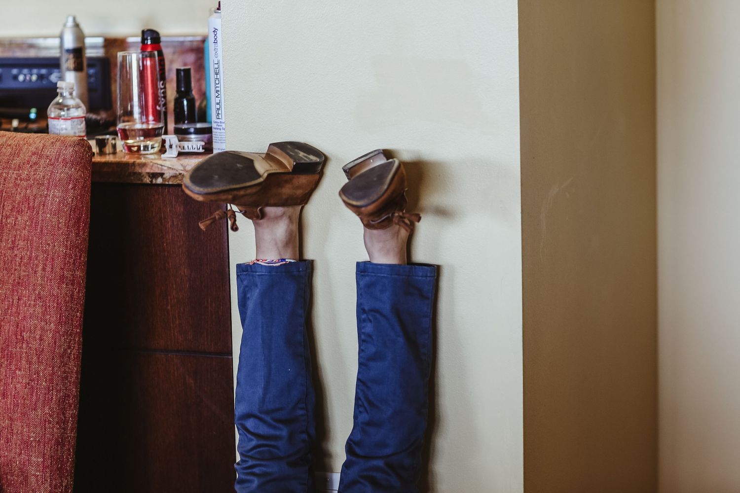 Groom relaxes with legs up wearing brown leather cowboy boots and blue suit pants against a wall.