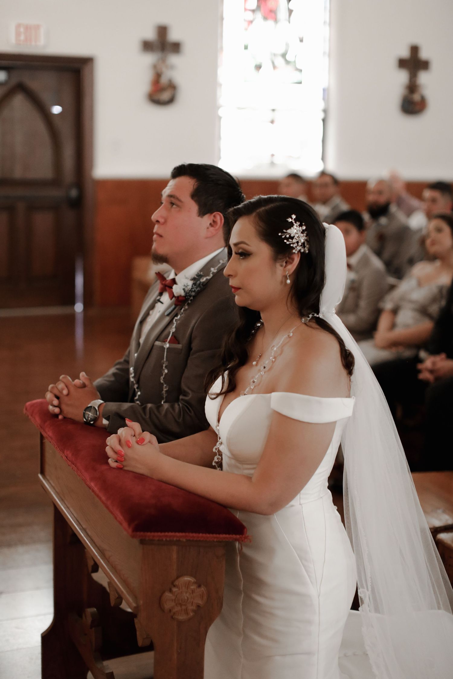 Bride and groom kneeling in prayer at church altar during traditional wedding ceremony.