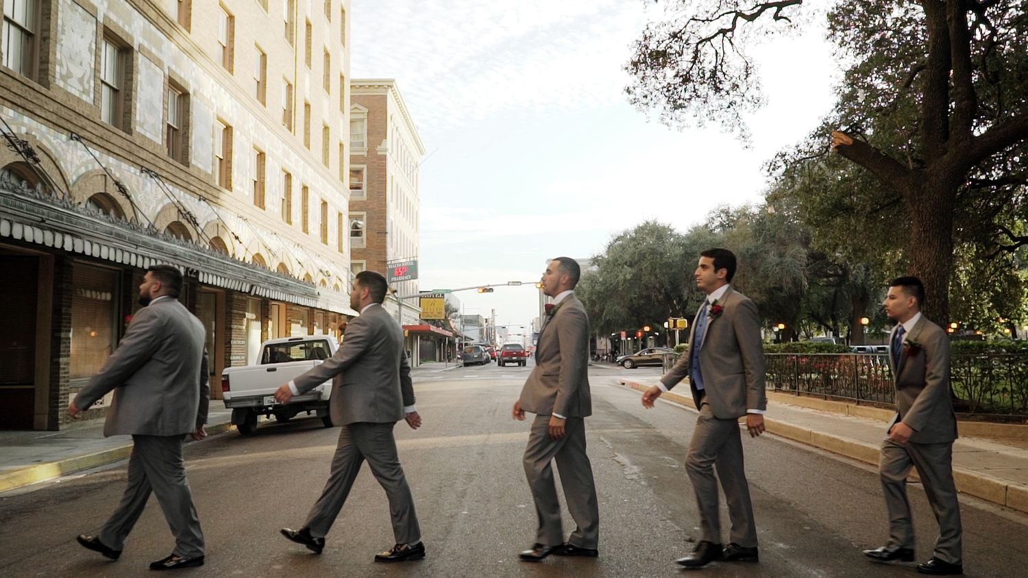 Groomsmen in grey suits cross a city street in a fun Beatles Abbey Road pose.
