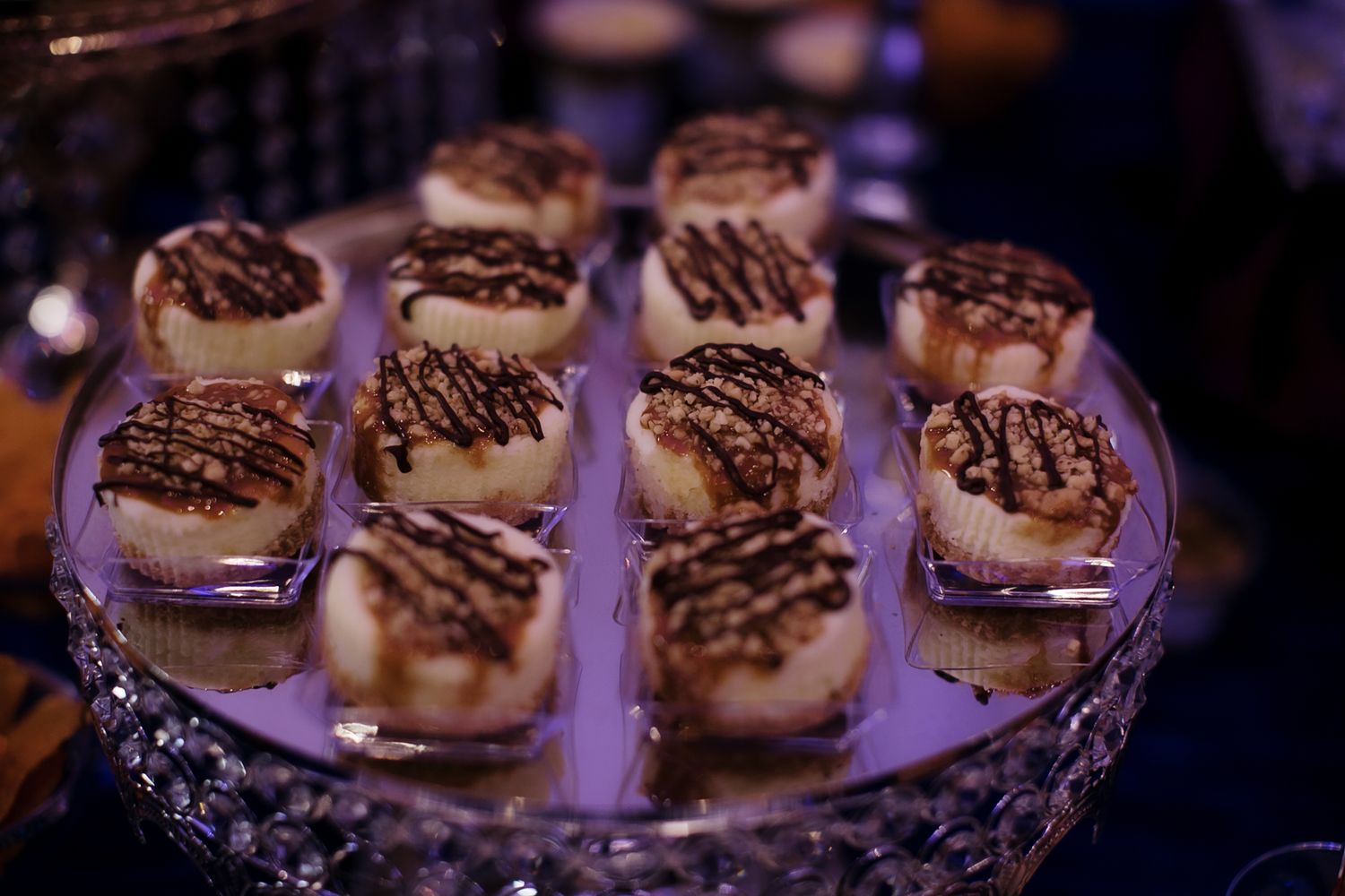 Elegant dessert display of chocolate-drizzled coconut macaroons on crystal cake stand.