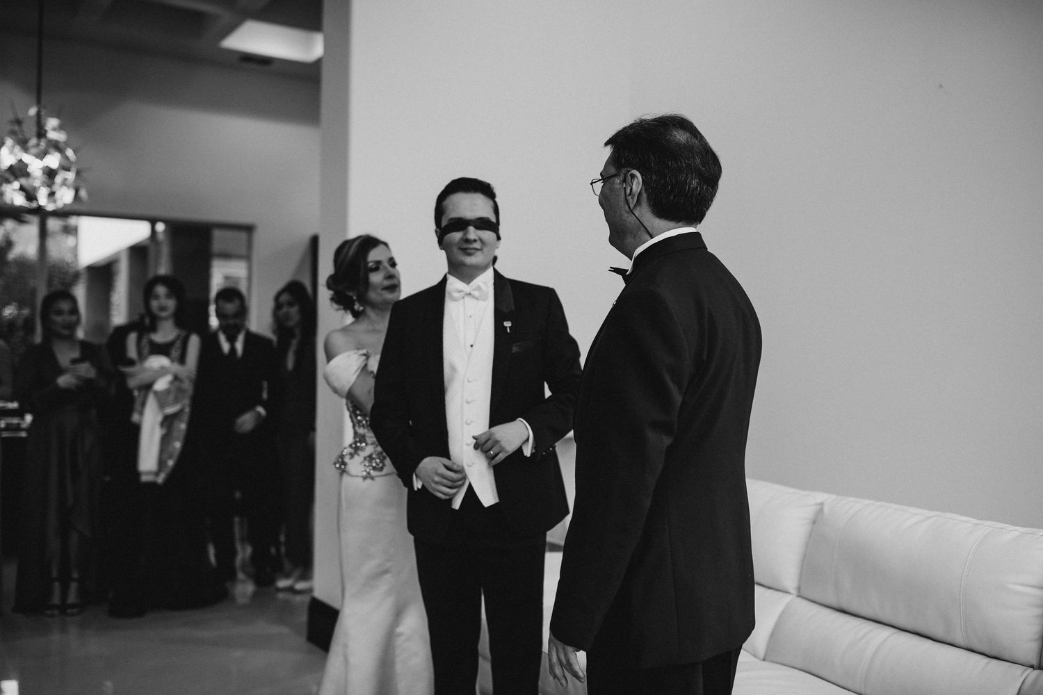 Bride and groom share a joyful moment with officiant during black and white wedding ceremony indoors.