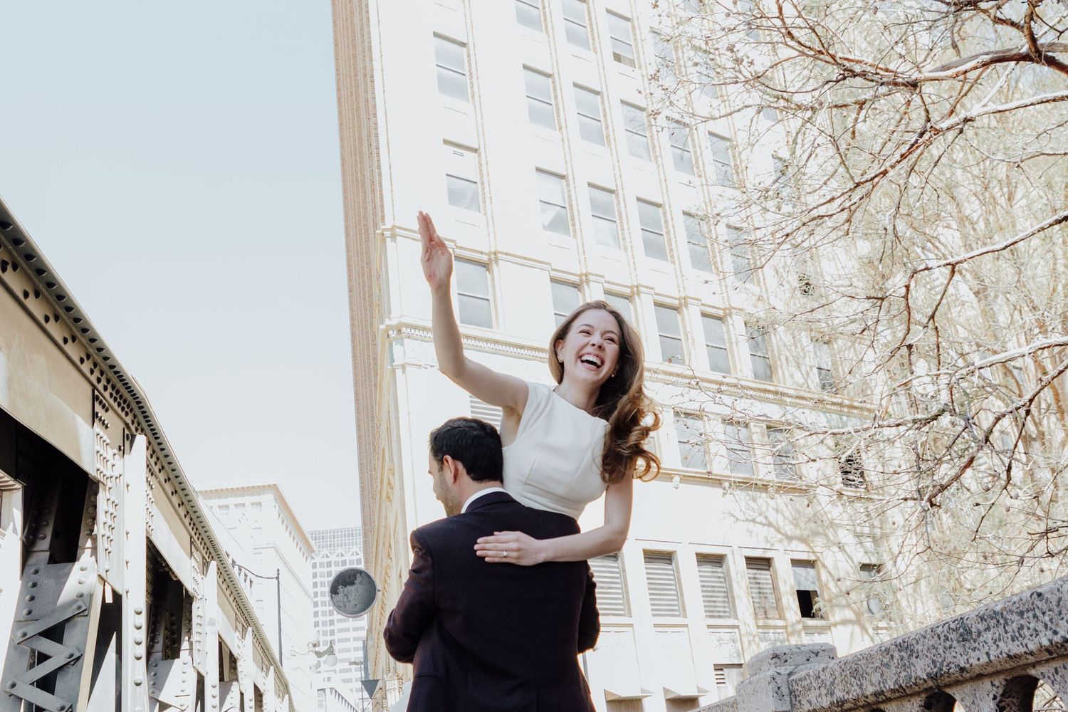 A joyful couple embracing and dancing in front of an urban building.