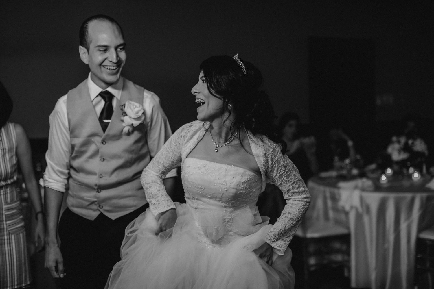 Bride and groom laughing together on the dance floor in black and white wedding photo.