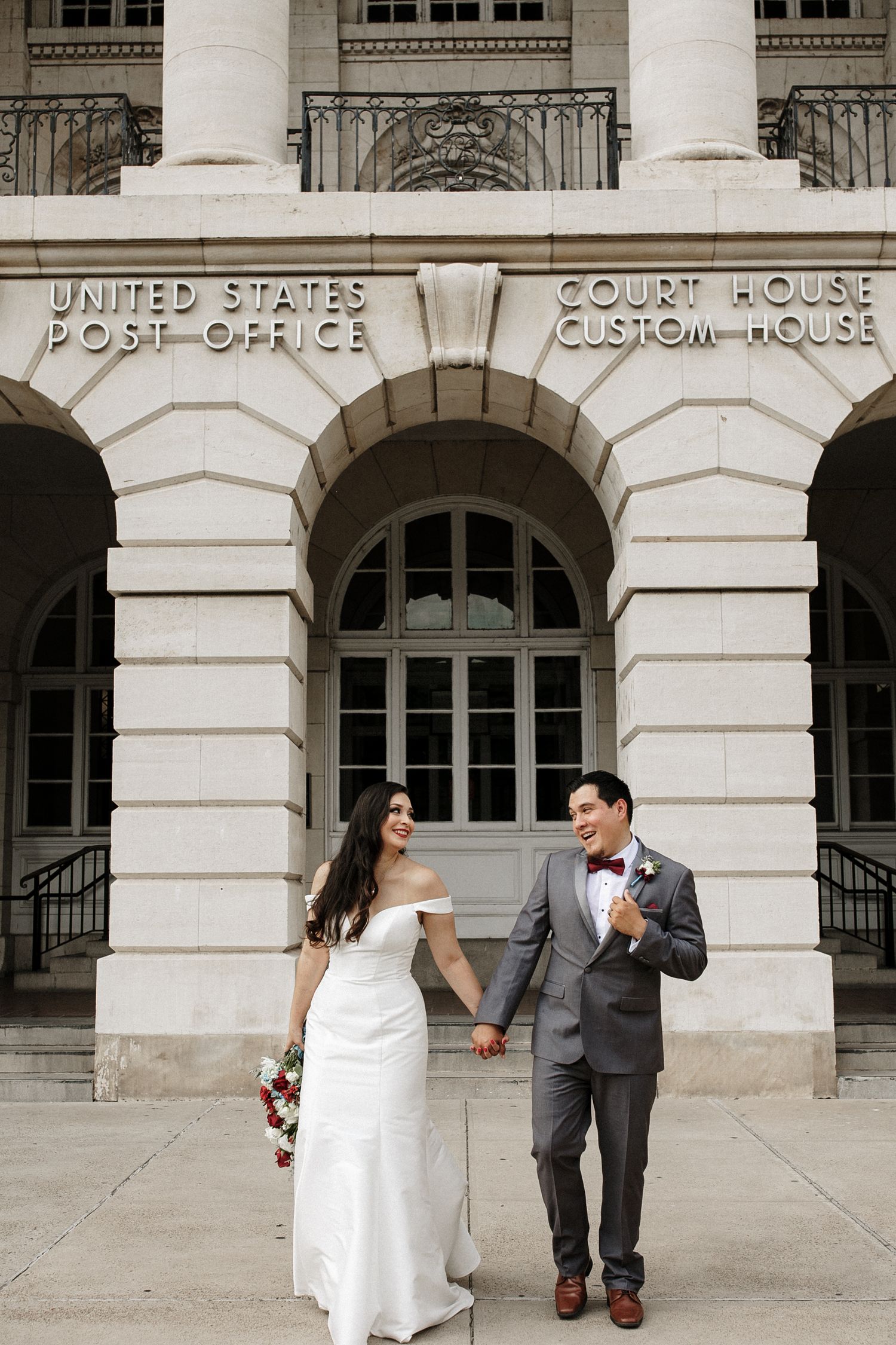 Bride and groom holding hands outside United States Post Office Court House.