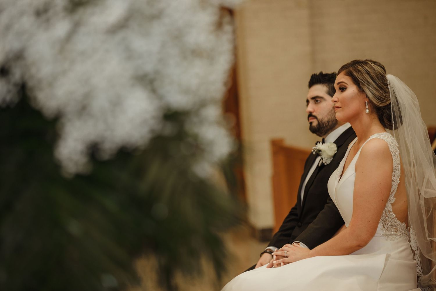 Bride and groom sitting together during wedding ceremony in church.