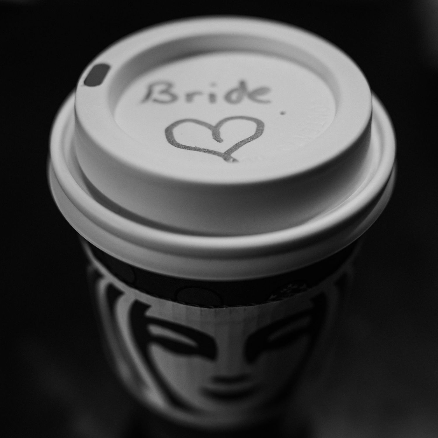 A black and white photo of a Starbucks cup with Bride and a heart written on the lid.