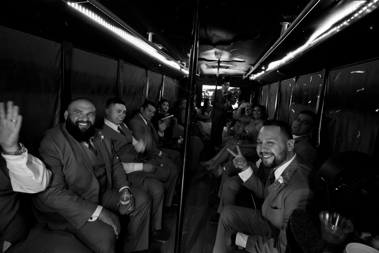 Black and white photo of groomsmen celebrating on party bus before wedding.
