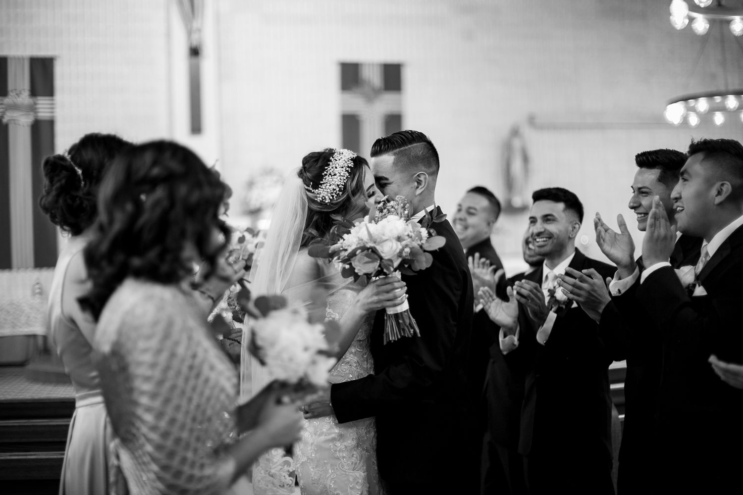 Black and white capture of a wedding celebration with guests cheering in a church setting.