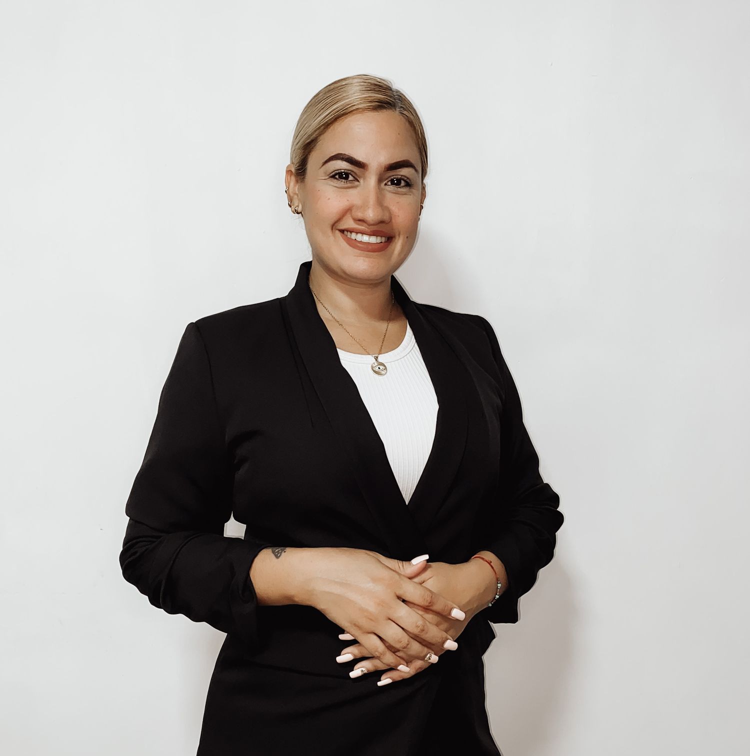Professional business headshot showing a posed photo in a black blazer and white top against a light background.