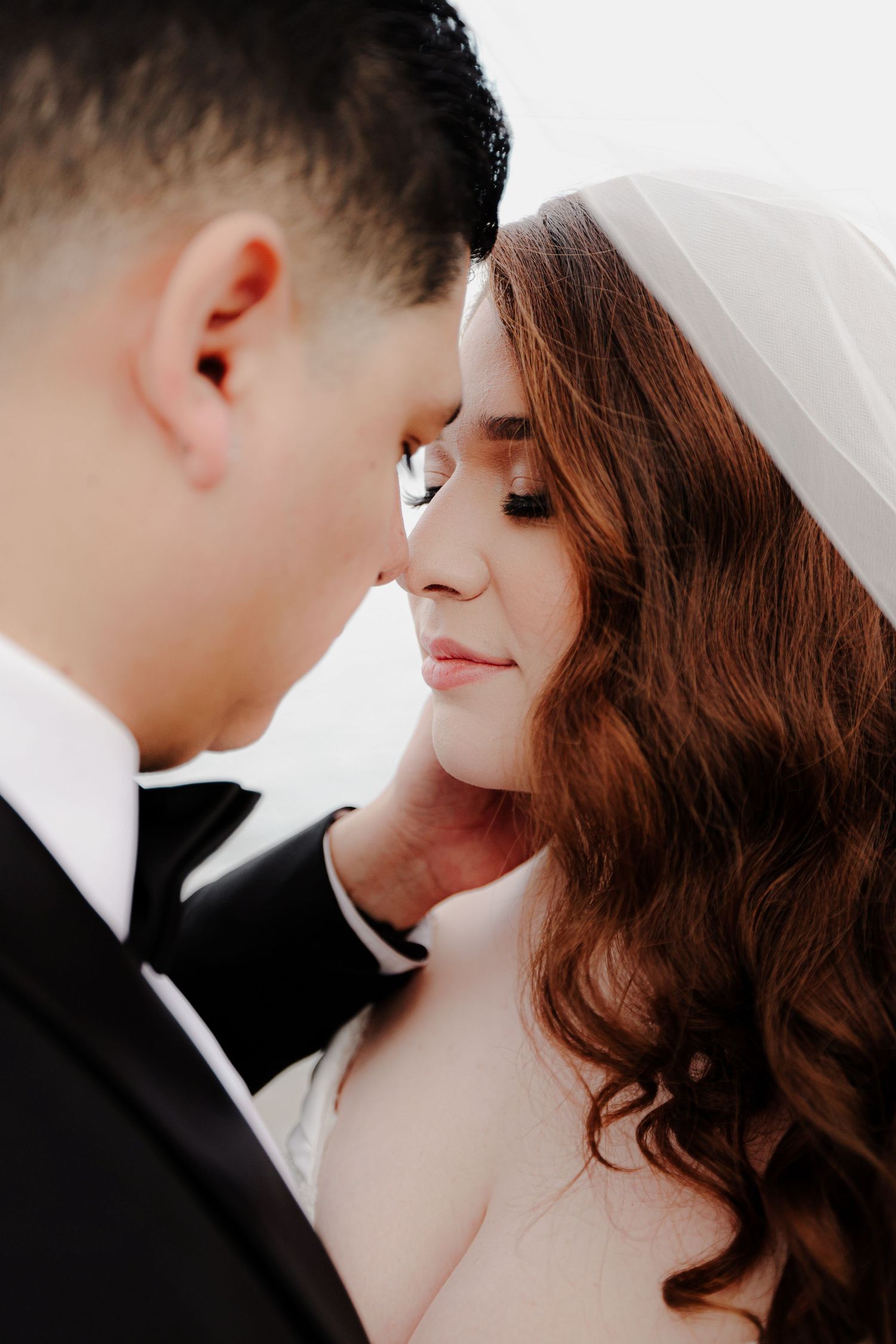An intimate close-up of a bride and groom sharing a tender moment with their faces nearly touching.